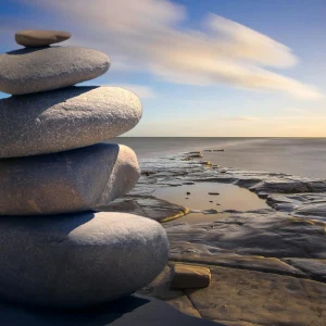 A serene stack of stones on the rocky seashore during a peaceful sunrise, embodying balance and zen.