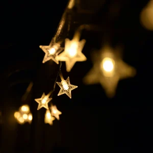Warm star-shaped fairy lights hanging elegantly in the night, creating a festive ambiance.