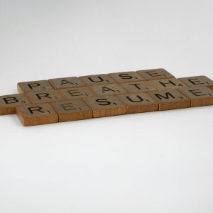 Scrabble tiles spelling 'Pause, Breathe, Resume' on a white background, symbolizing mindfulness and relaxation.